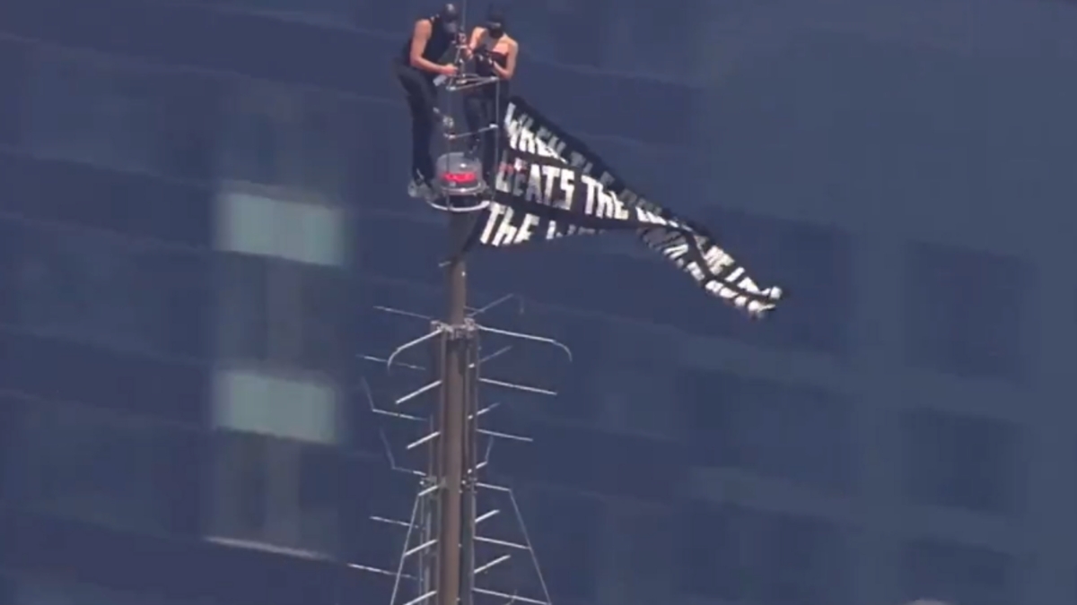 Dos personas suben a la cima del Empire State Building y despliegan una pancarta a favor de la paz